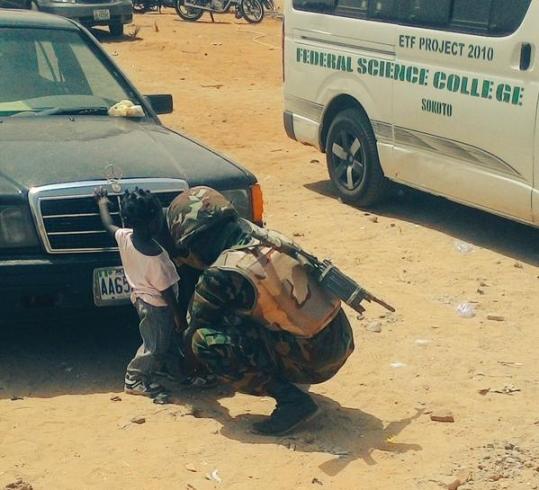 Nigerian soldier helps little girl put on sandals